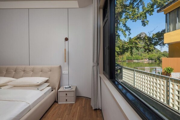 Un dormitorio con cama, mesita de noche y ventana con vistas a un lago.