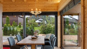 Un comedor moderno con una mesa de madera, sillas y una araña.