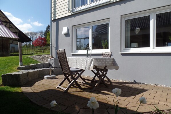 Un patio con mobiliario exterior, una mesa y sillas.