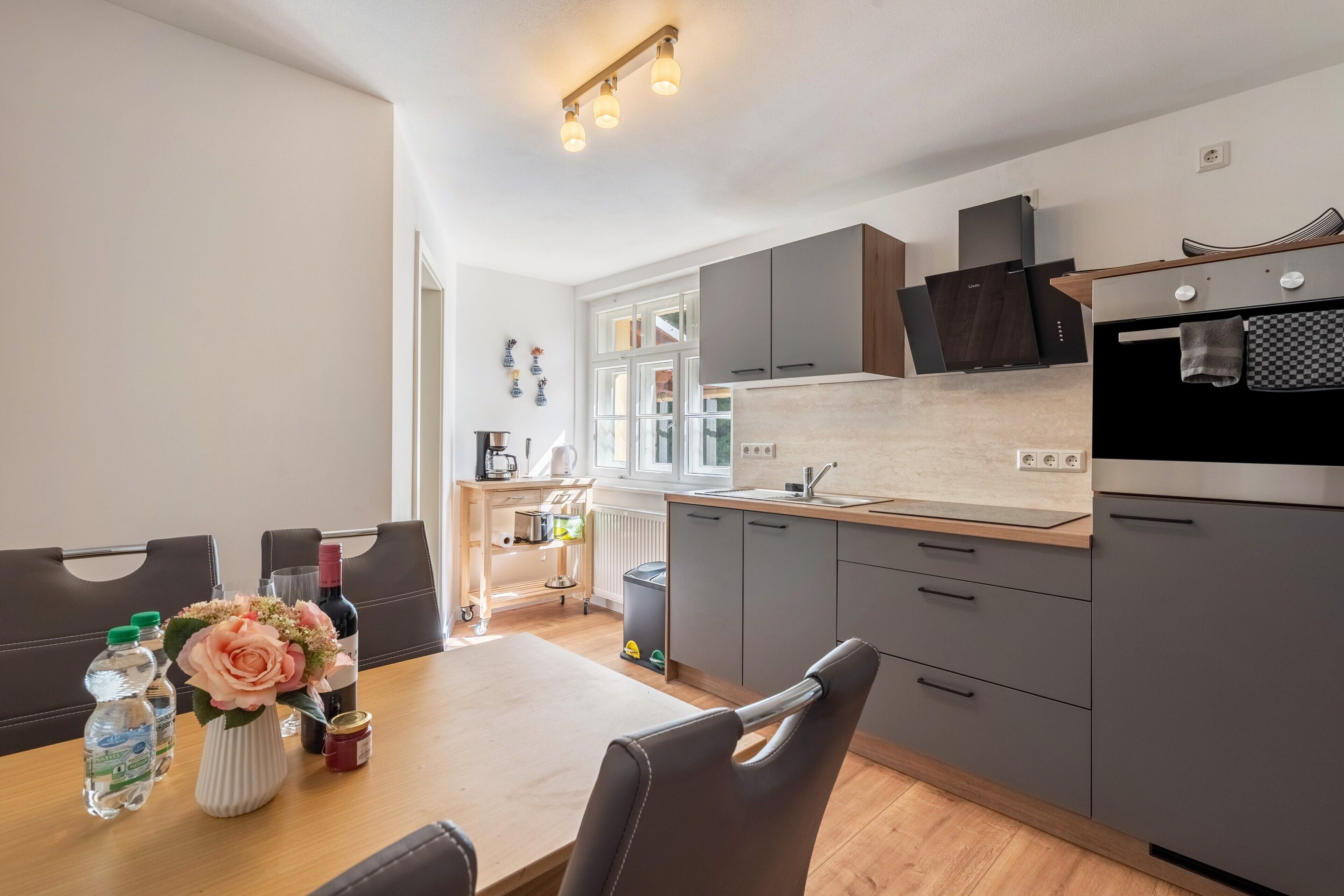 Eine moderne Küche mit grauen Schränken, einer Holz Arbeitsplatte und einem Essbereich mit Tisch und Stühlen.