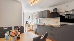 Une cuisine moderne avec des meubles gris, un plan de travail en bois et un coin repas comprenant une table et des chaises.