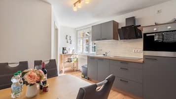 Eine moderne Küche mit grauen Schränken, einer Holz Arbeitsplatte und einem Essbereich mit Tisch und Stühlen.