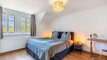 A bedroom with a bed, a nightstand, a mirror, a window with curtains, and a ceiling light fixture.