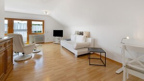 Una sala de estar moderna con un sofá blanco, una mesa de centro negra y un armario de madera.
