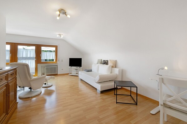 A modern living room with a white sofa, a black coffee table, and a wooden cabinet.