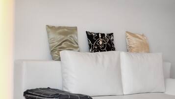 A white sofa with three pillows in different patterns and textures.