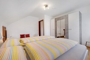 A bedroom with two beds, a wardrobe, and a mirror.
