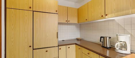 A kitchen with wooden cabinets, a countertop, a kettle, and a coffee maker.