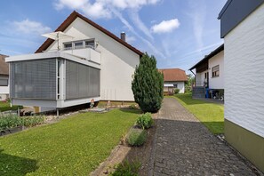 A modern house with a sloped roof, a large window, and a well-maintained lawn.