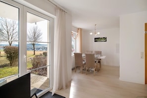 Une chambre moderne dotée d’une grande porte-fenêtre coulissante, d’un coin repas avec une table et des chaises, et offrant une vue sur l’extérieur.