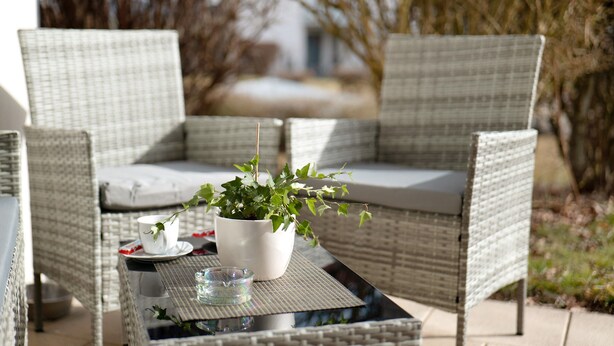 A wicker outdoor seating area with a table, chairs, and a potted plant. - Quiet Apartment in Bad Saulgau with Mountain View, Private Terrace and Wi-Fi (Bad Saulgau)