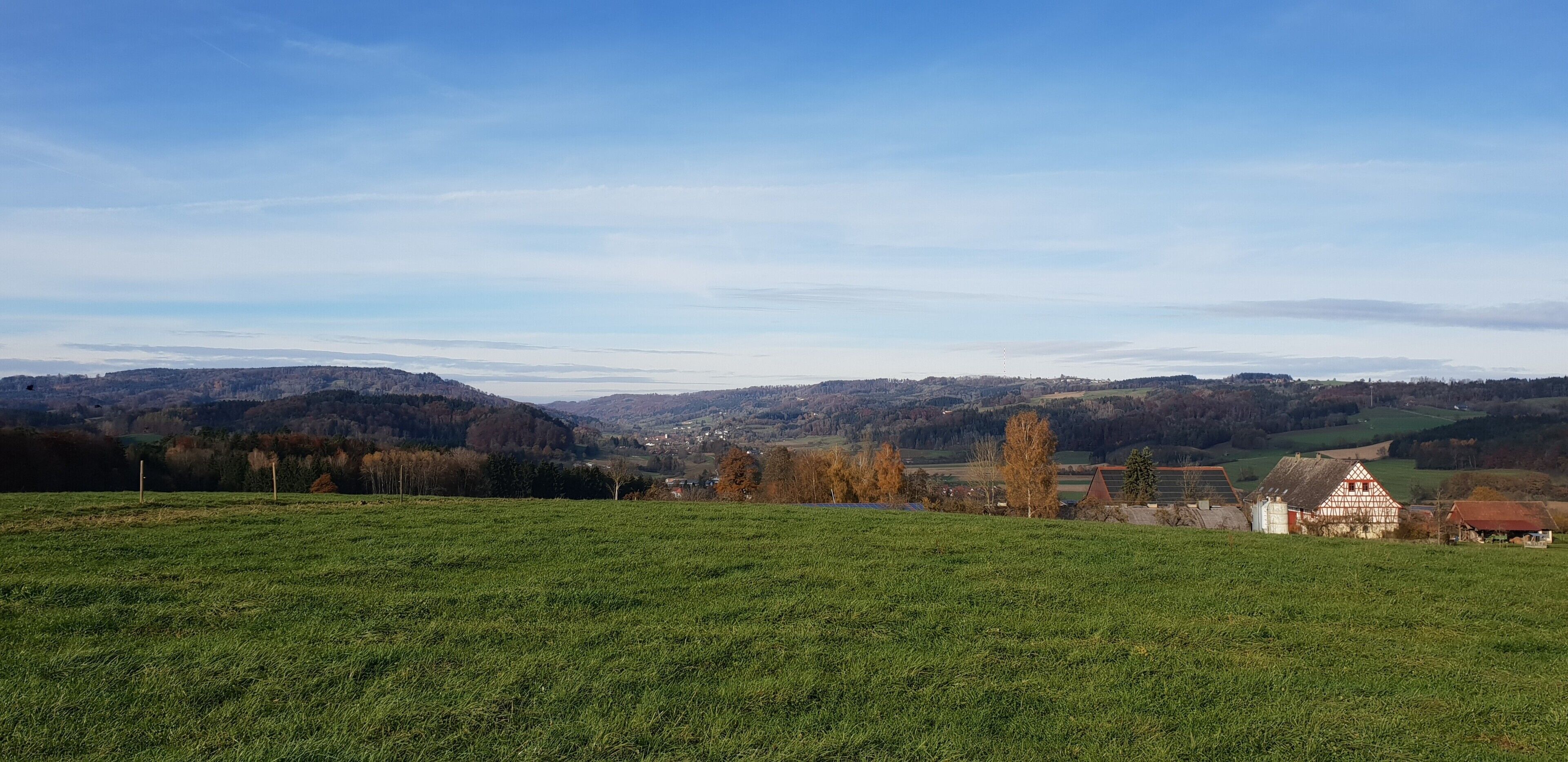 A rural landscape with a green field, a traditional house, and distant hills.
