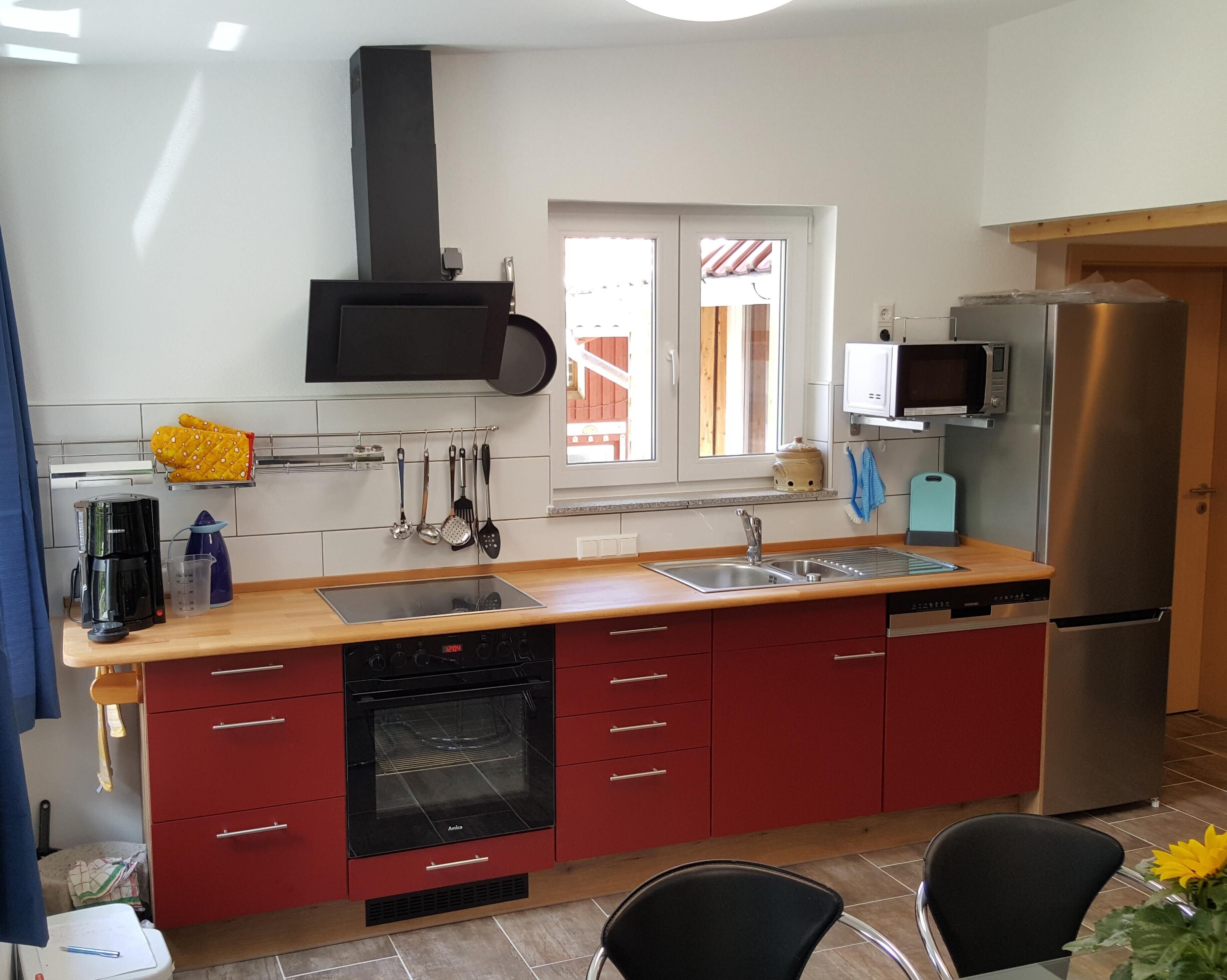 Una cocina moderna con horno empotrado, refrigerador de acero inoxidable y ventana con vista al exterior.