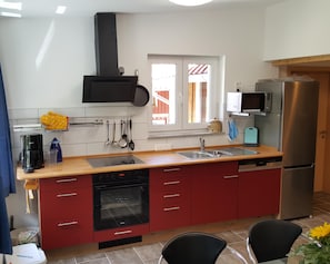 Una cocina moderna con horno empotrado, refrigerador de acero inoxidable y ventana con vista al exterior.