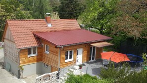 Una casa de madera de dos pisos con techo de tejas rojas, un pequeño porche y un trampolín en el patio trasero.