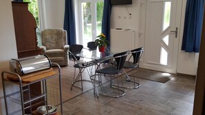 Un comedor con una mesa, sillas, una cafetera, un sofá y un televisor montado en la pared.
