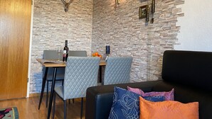 Un comedor con pared de piedra, un reloj y una mesa con sillas.