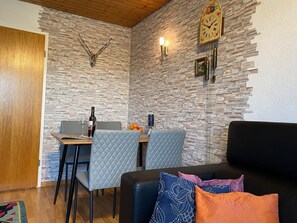 A dining area with a stone wall, a clock, and a table with chairs.