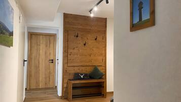 Ein Flur mit Holzboden, einer Sitzbank mit Kissen, einer Tür und einer wandmontierten Lampe.