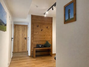A hallway with wooden flooring, a bench with a cushion, a door, and a wall-mounted light fixture. - Apartment 'Janßen-Wehrle' with Mountain View, Private Terrace and Wi-Fi (Titisee-Neustadt)