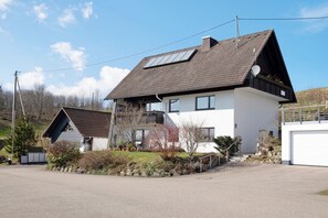 A two-story house with a sloped roof, solar panels, a garage, and a well-maintained garden.