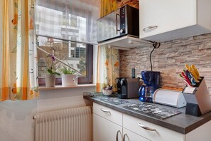 A kitchen with a microwave, coffee maker, and utensils on the counter.