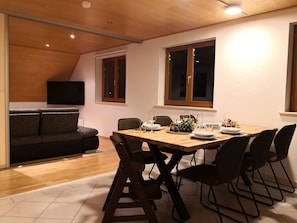 A dining area with a wooden table, black chairs, and a black sofa.