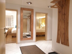 A hotel room with a wooden wardrobe, a mirror, a bed, and a bathroom visible through an open door.