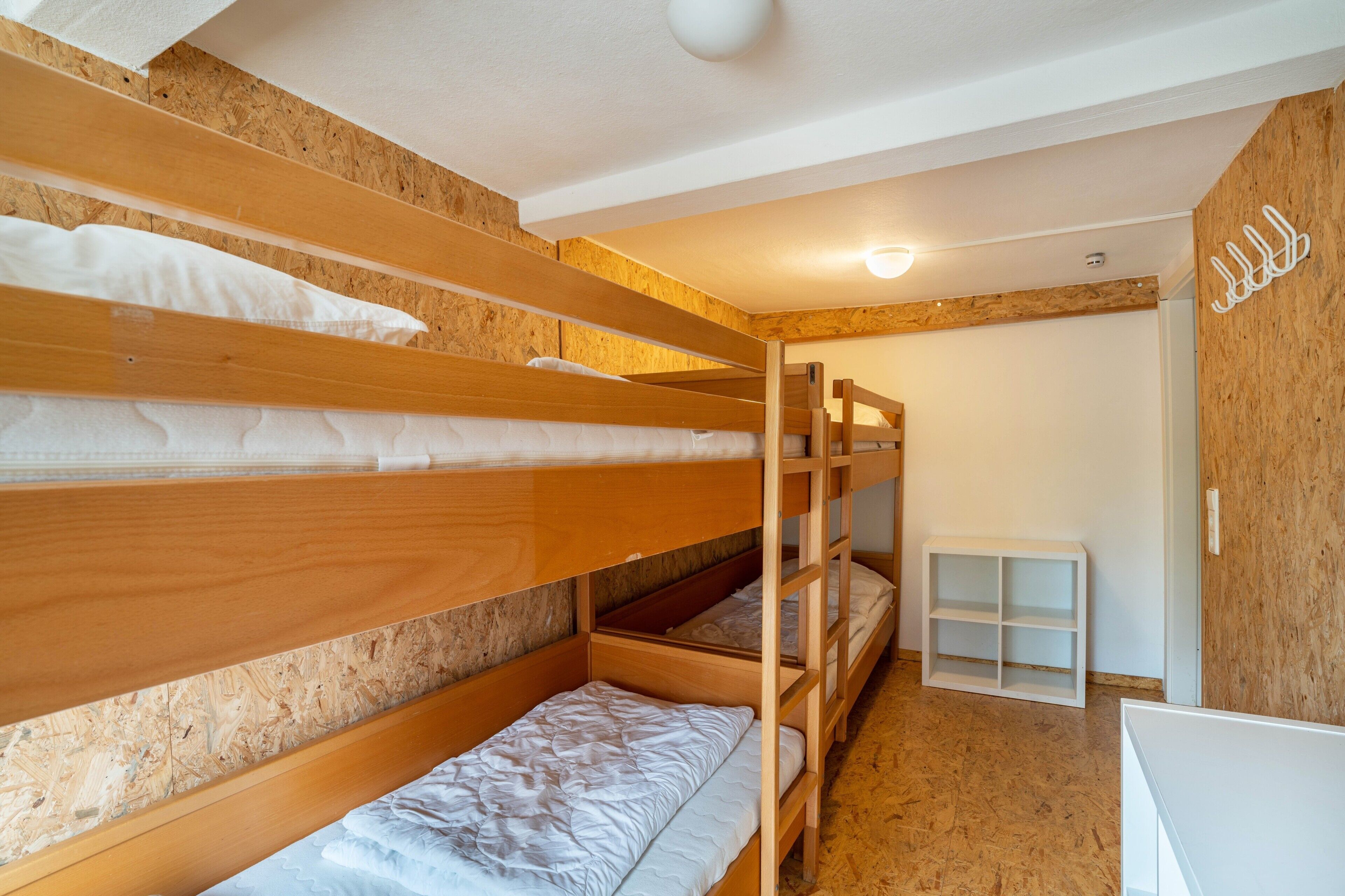 A bunk bed room with wooden walls and a white shelf unit.