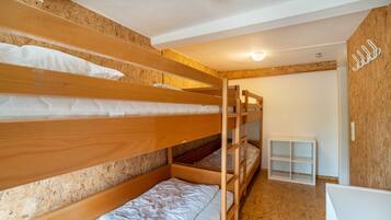 A bunk bed room with wooden walls and a white shelf unit.