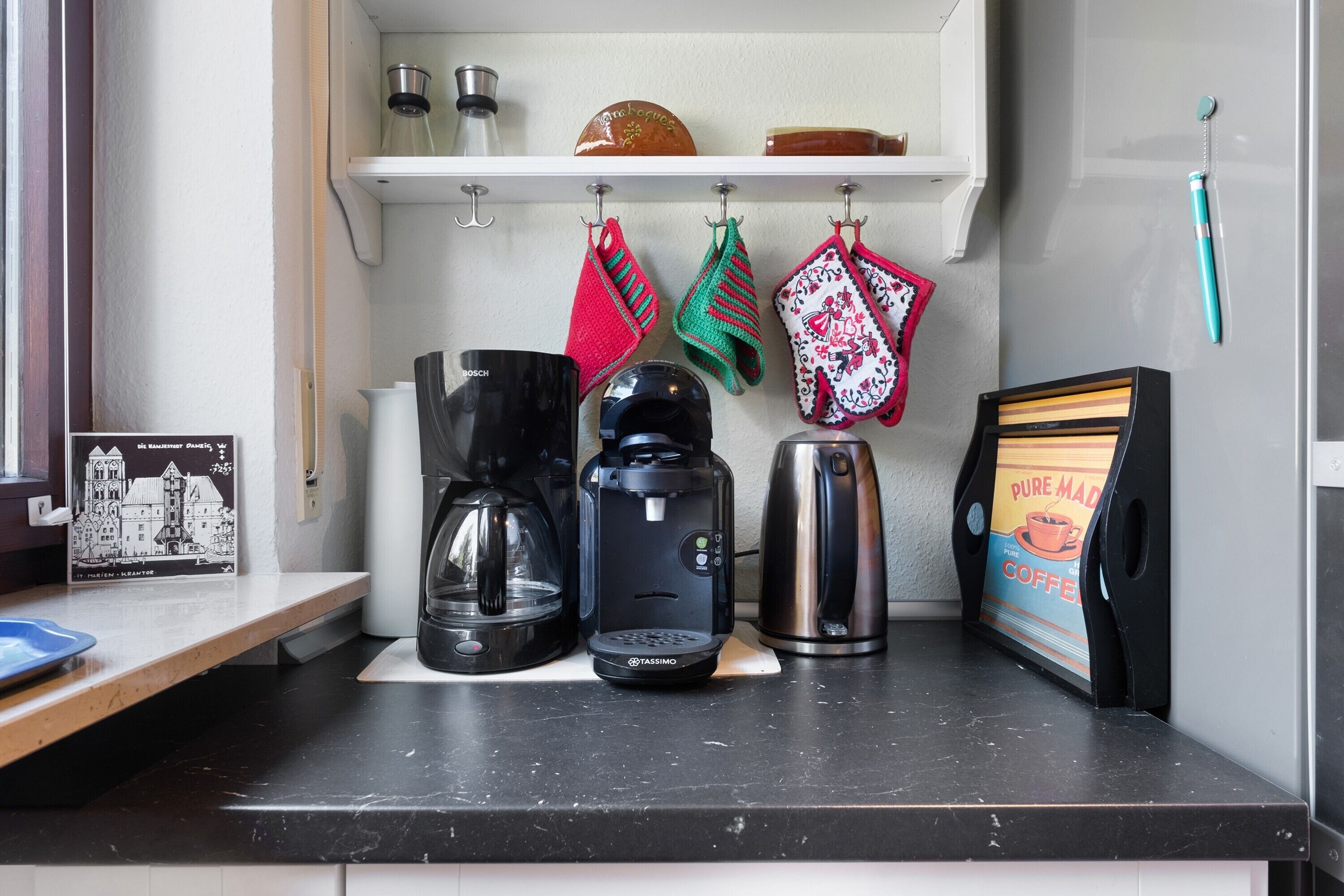 Een keukentafel met een koffiezetapparaat, een waterkoker en een houder voor koffiecups.