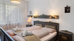 Ein Schlafzimmer mit einem Doppelbett, zwei Nachttischen, einer Hängelampe und einem an der Wand befestigten Spiegel.