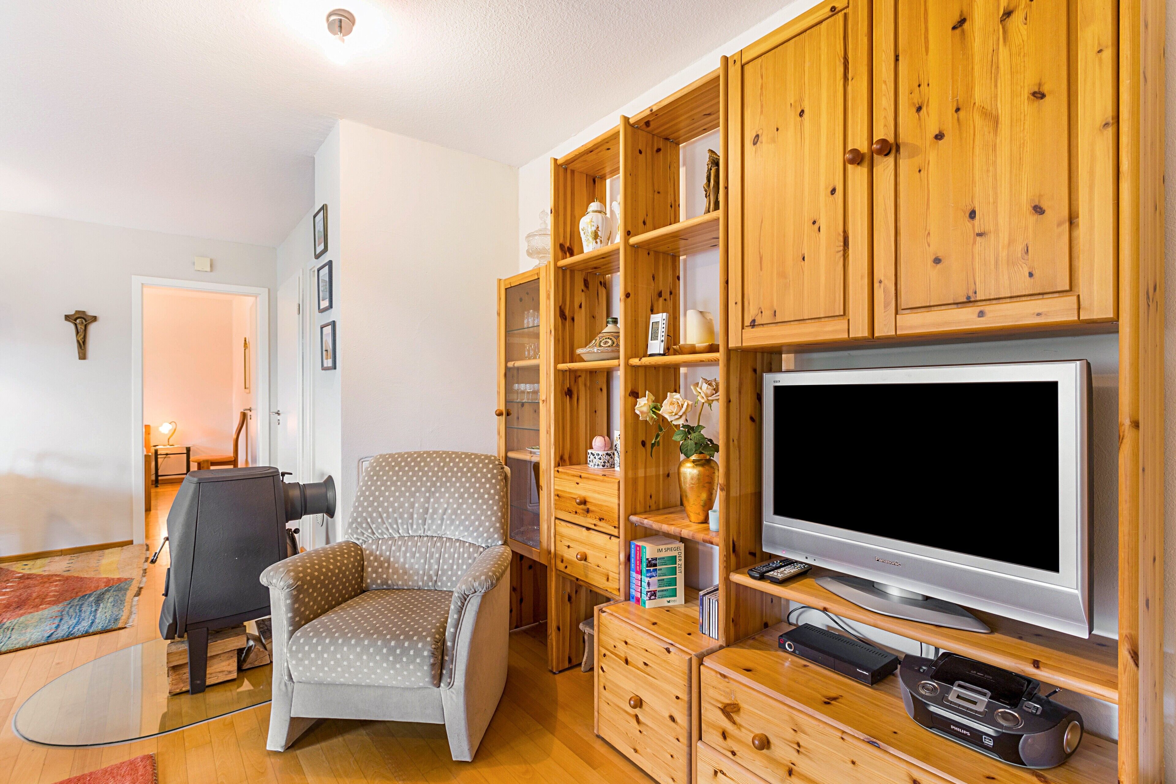 A living room with a television, wooden cabinets, a polka-dotted chair, and a fireplace.