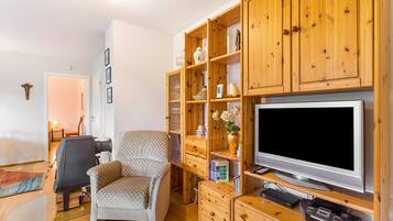 Een woonkamer met een televisie, houten kasten, een stoel met stippen en een open haard.