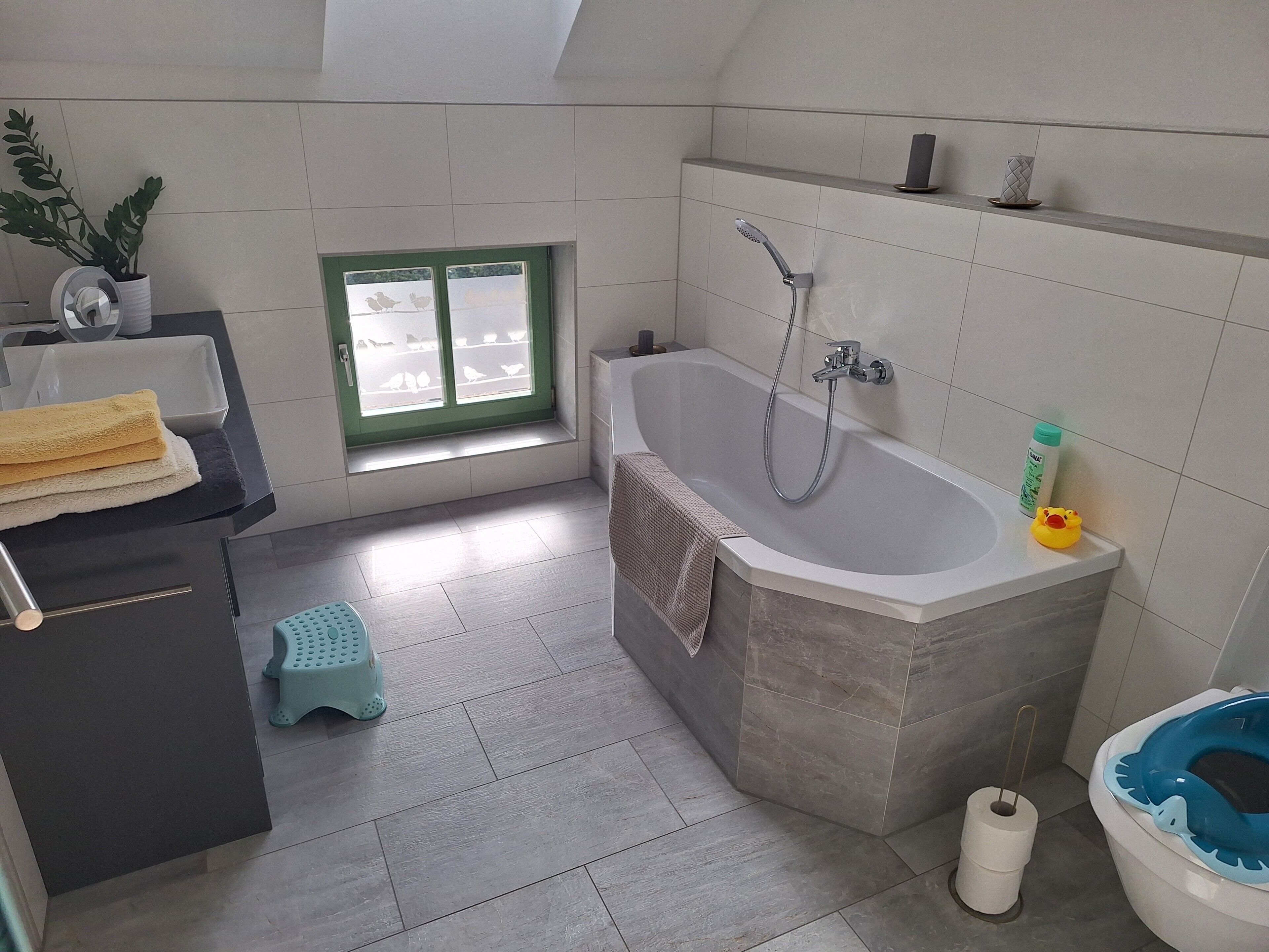 A bathroom with a bathtub, toilet, and window.