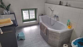 A bathroom with a bathtub, toilet, and window.