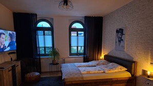 Ein Schlafzimmer mit Bett, Fernseher, Topfpflanze und Kamin.