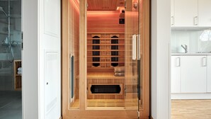 Un sauna con paredes de madera, puerta de cristal y panel de control.