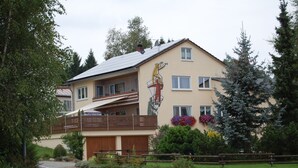A two-story building with a balcony, a mural, and a wooden fence.