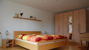 A bedroom with a wooden bed, bedside tables, a wardrobe, and a mirror.
