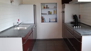 A compact kitchen with a sink, cabinets, and a built-in shelf unit.