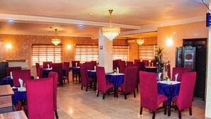 A restaurant with red chairs and blue tablecloths, featuring chandeliers and a tiled floor. - DEES HOTELS APARTMENT & SUITES (Lagos)