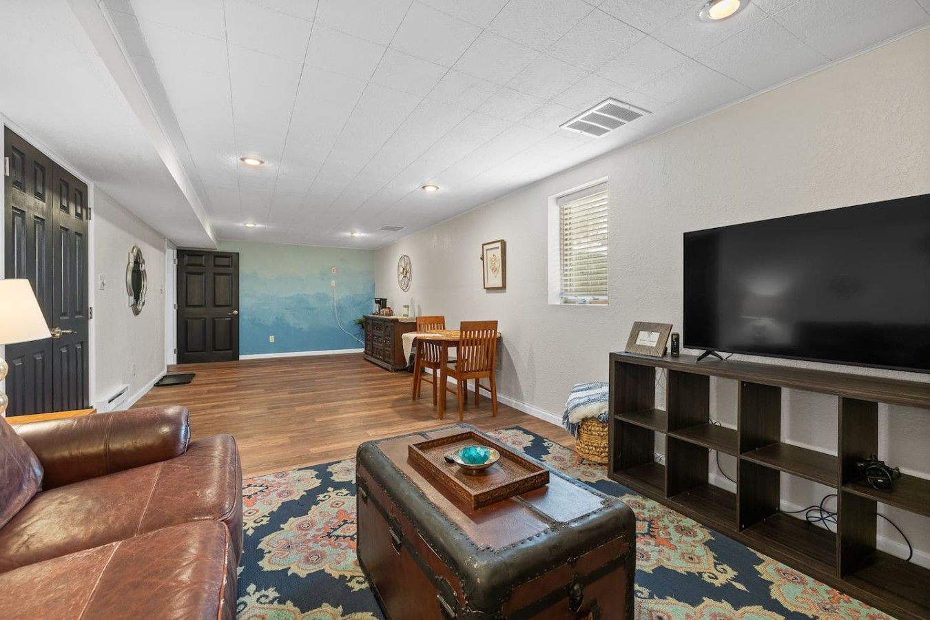 A living room with a television, leather sofa, wooden coffee table, and a patterned rug.
