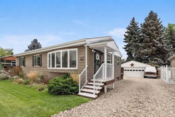 A single-story mobile home with a front porch and a covered garage.