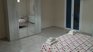A bedroom with a large wardrobe, a bed with a polka dot bedspread, and a window with blinds. - Vacation home Perla Marina (Porto Empedocle)