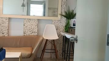 Een moderne woonkamer met een stenen muur, een bank, een witte fauteuil, een bijzettafeltje en een deur.
