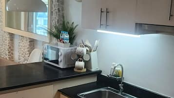 Een moderne keuken met een stenen muur, een klok, een waterkoker en een broodrooster.