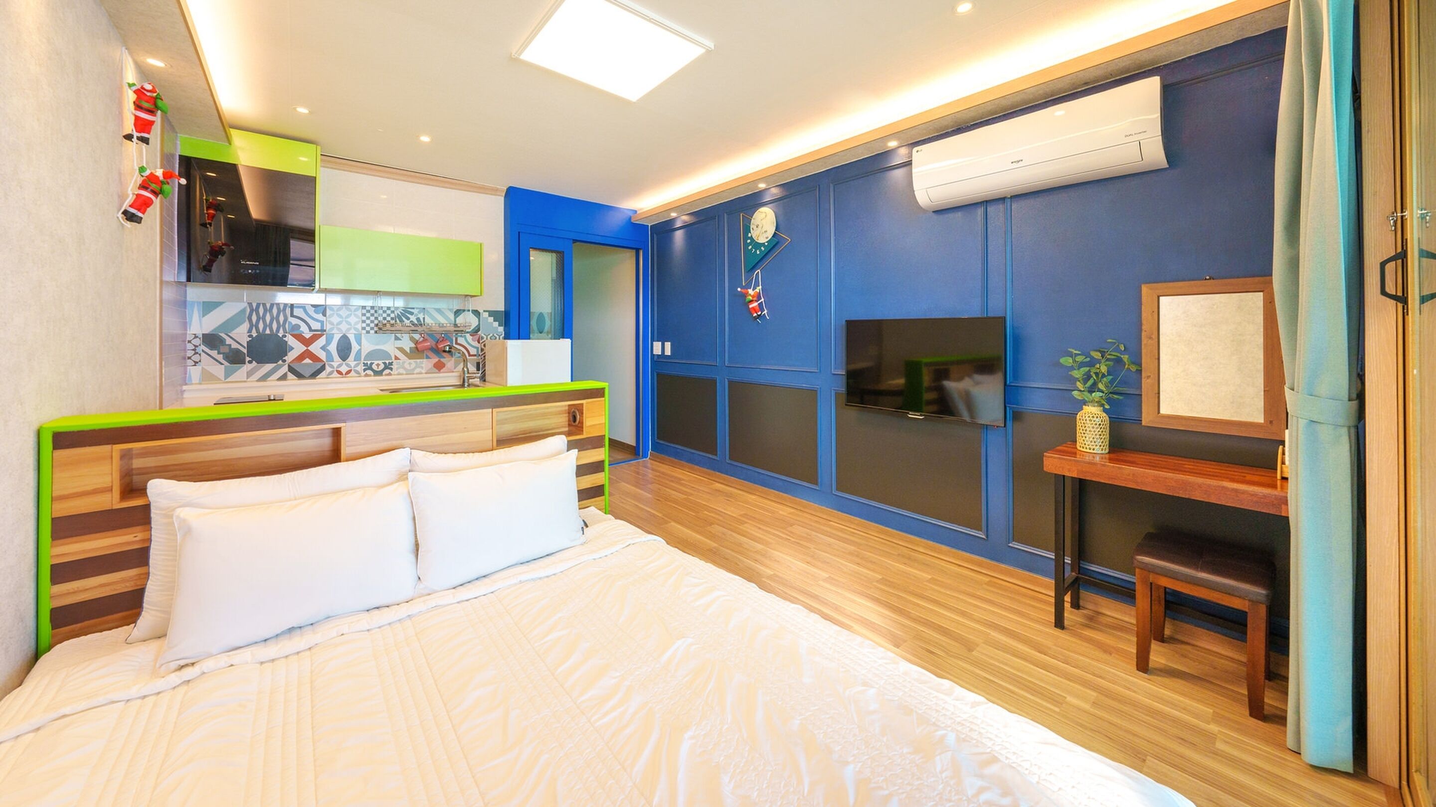 A modern bedroom with a bed, a desk, and a TV.