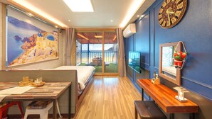 Une chambre d’hôtel avec un lit, un bureau, une télévision et une vue sur la plage.