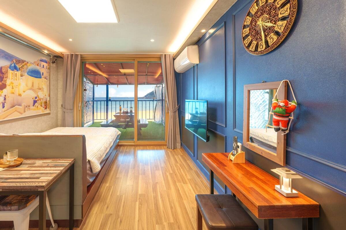 Une chambre d’hôtel avec un lit, un bureau, une télévision et une vue sur la plage.